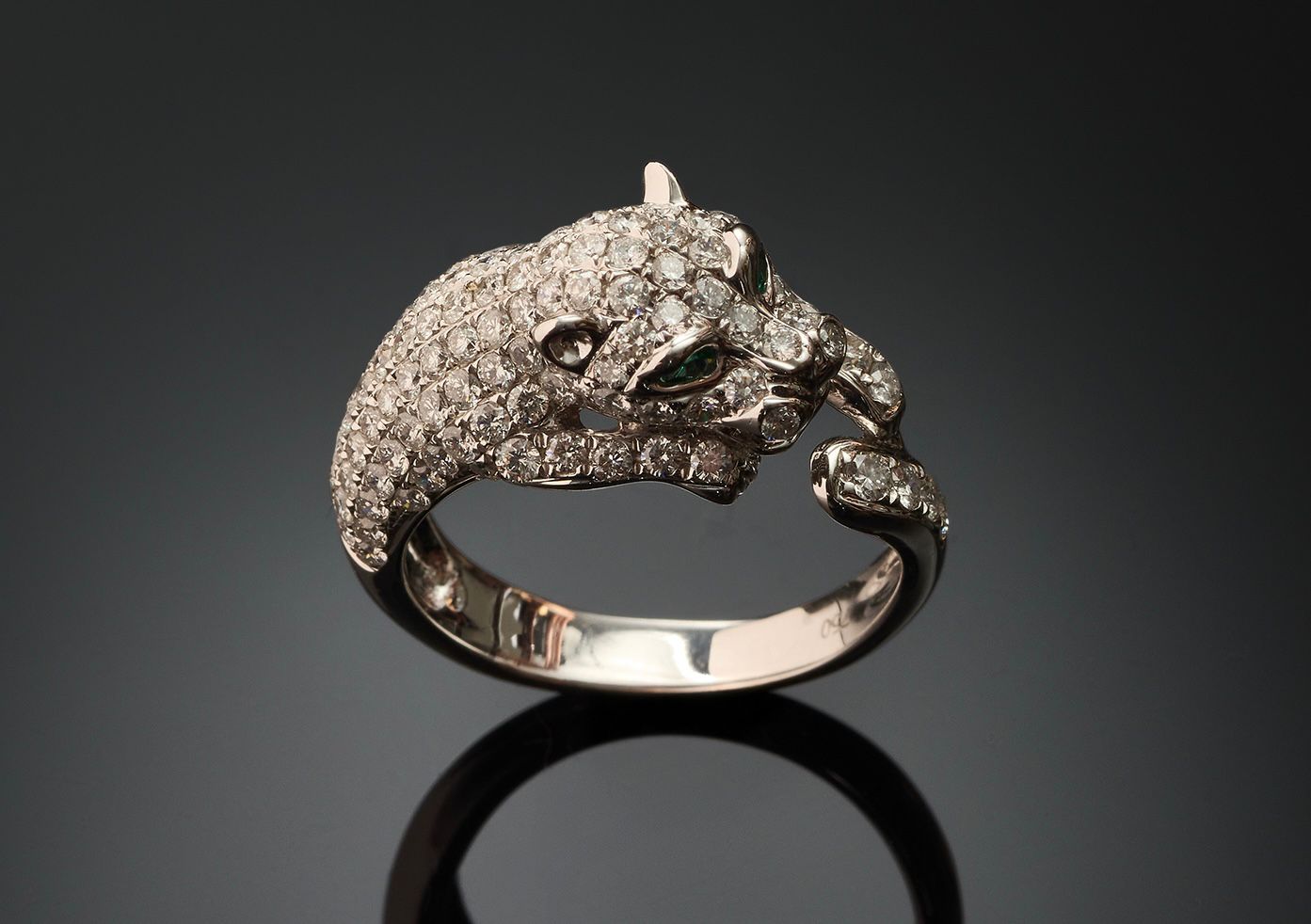 Silver panther-shaped ring with gemstones on a reflective surface